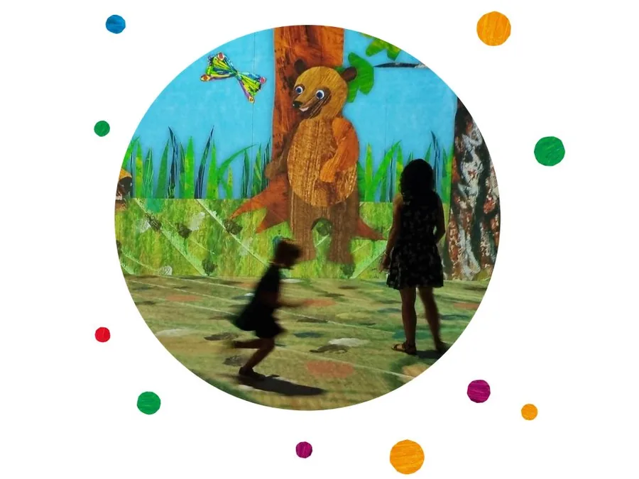 A child running past a projected Eric Carle bear inside the immersive experience