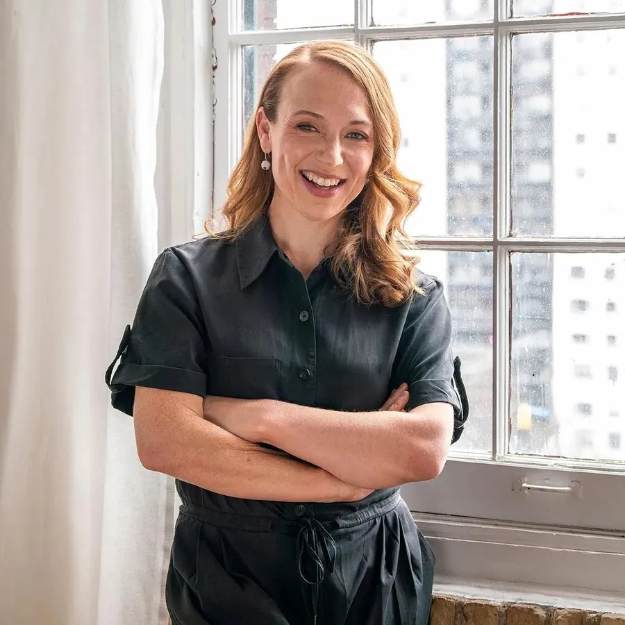 Olivia Ansell standing by a window, arms folded, smiling